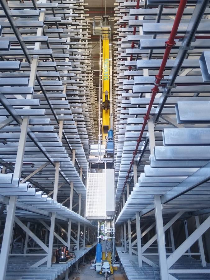 High-bay warehouse aisle with a Siemens stacker crane running between the racking
